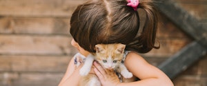 A young girl cuddling an orange kitten