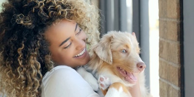 woman with curly hair holding a dog