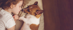 A young girl sleeping in bed with her dog