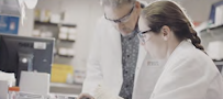 A man and woman in lab coats looking at a computer