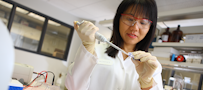 A woman in a lab coat holding a pipette